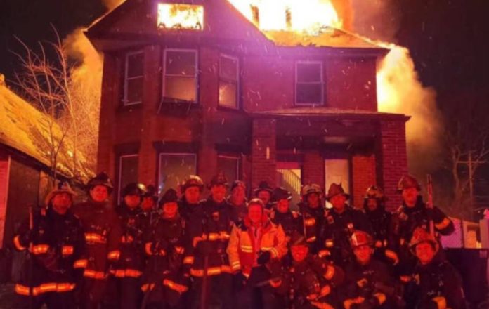The controversy photo that surrounds a group of Detroit firefighters smiling in front of a burning house