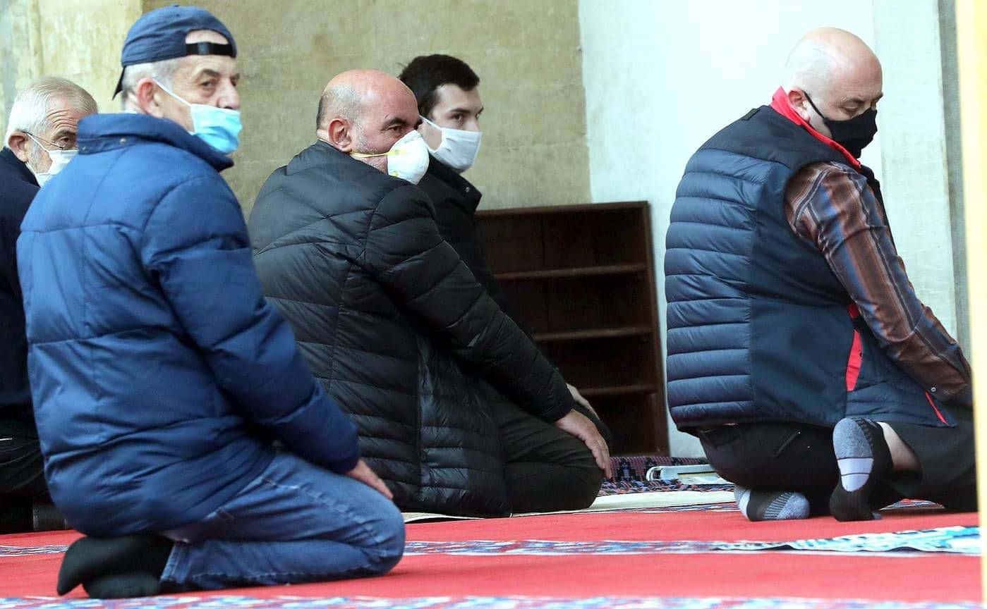Bosnian Muslim men in protective masks praying in Sarajevo Bosnia