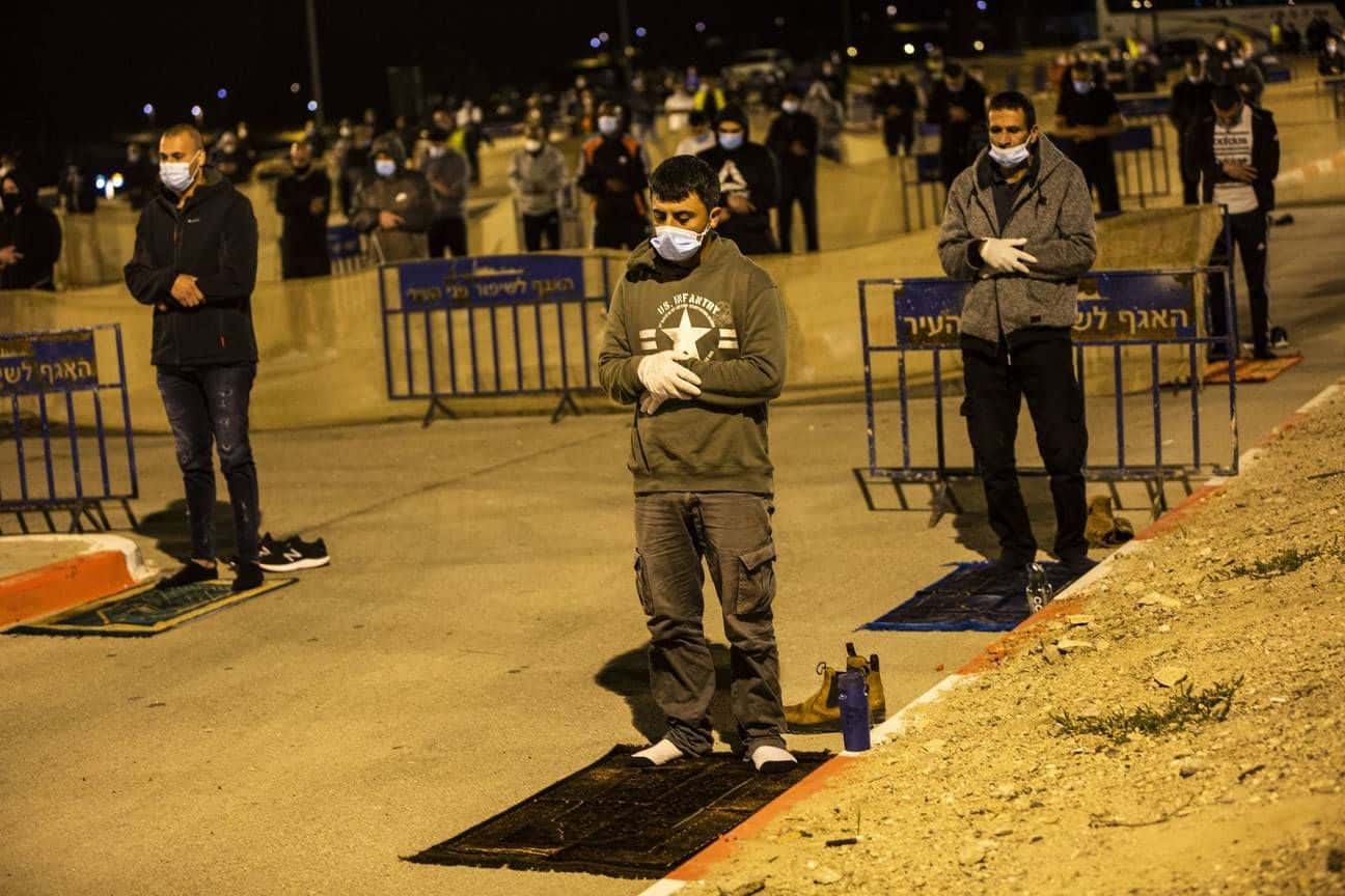Palestinian and Israeli Arab men maintain a distance of 2 meters and wear protective masks amid the COVID-19 pandemic, while praying in a parking lot in the ancient port city of Jaffa, in Tel Aviv